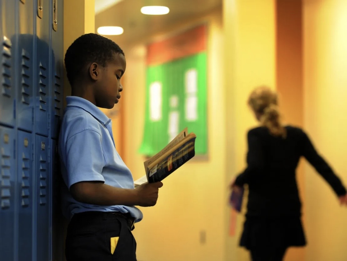 A student reading a book in a school hallway